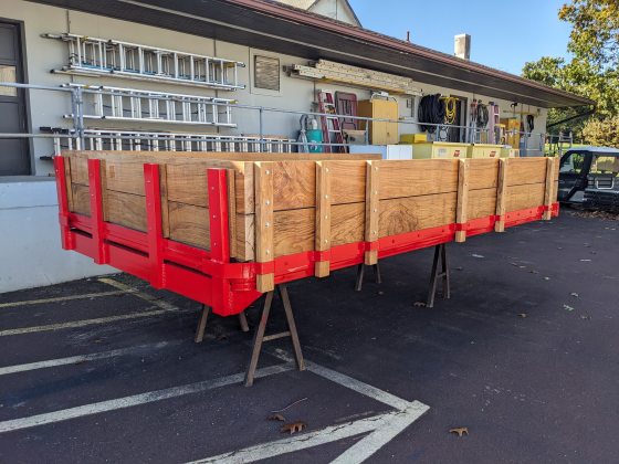 A wooden truck bed uninstalled and resting in a parking lot.